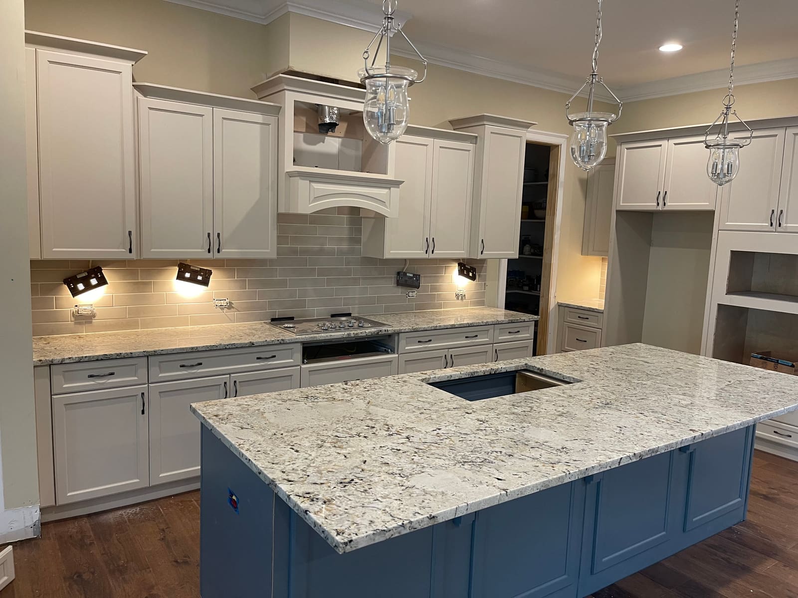 Finished kitchen with blue island, granite counters, and white perimeter cabinets