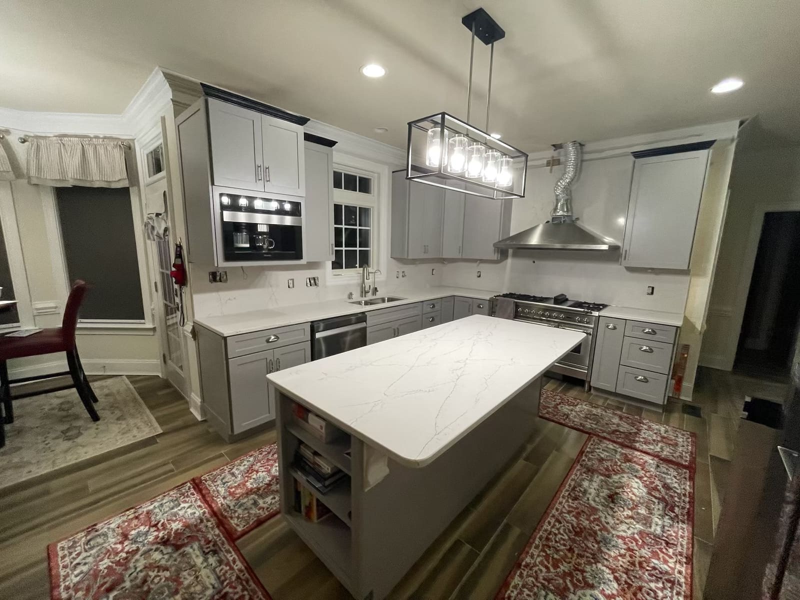 Remodeled kitchen with gray shaker cabinets, quartz island, pro-style range, and built-in coffee machine