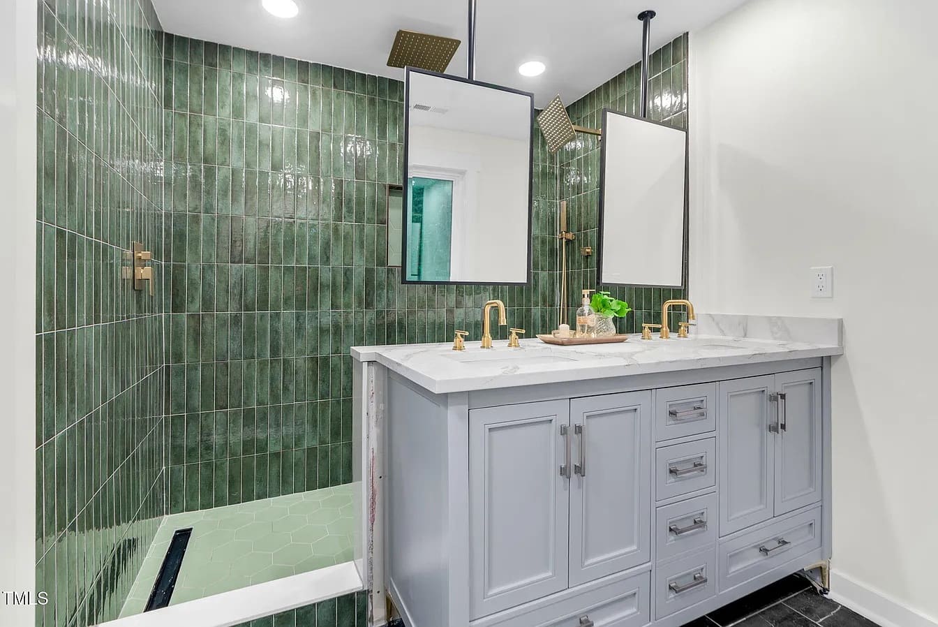 Remodeled bathroom with green tile walk-in shower and marble-top double vanity