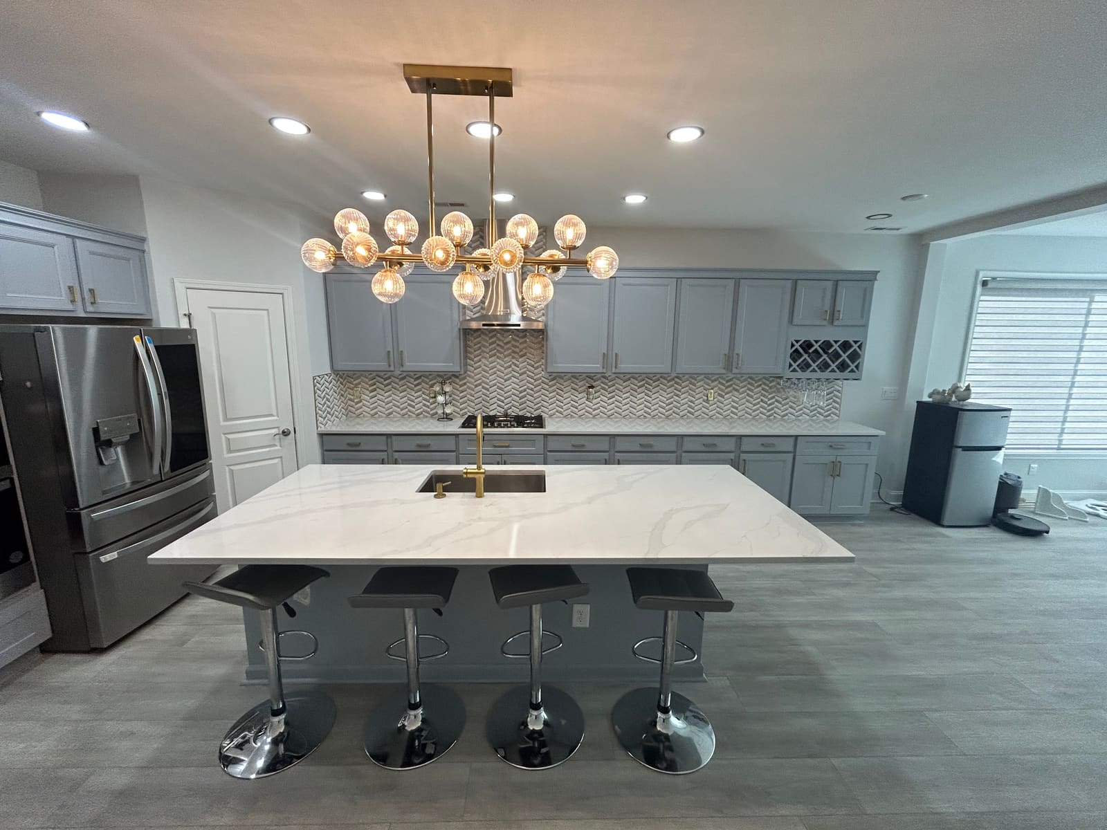 Remodeled kitchen with oversized quartz island and statement chandelier