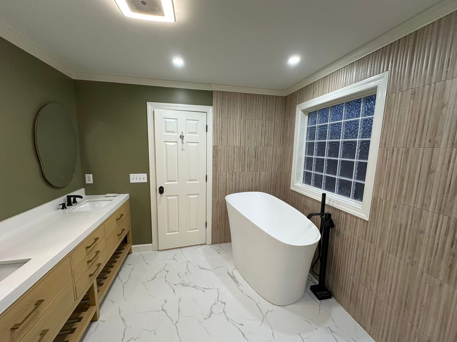 Remodeled bathroom with freestanding soaking tub and slat accent wall